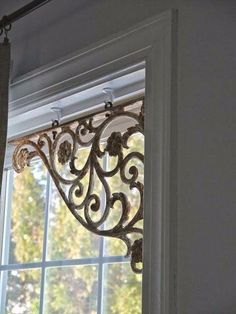 a window with an ornate iron design on it's side and a curtain rod in the middle