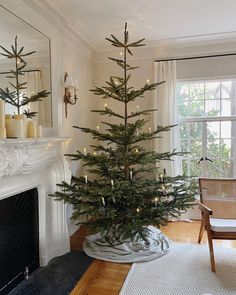 a living room with a christmas tree in the corner and candles on the fireplace mantel