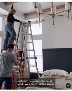 two people standing on ladders in a room