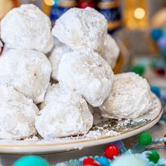 a plate filled with snowball cookies on top of a table next to candy balls