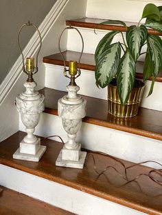 two marble urns sitting on top of a set of stairs next to a potted plant