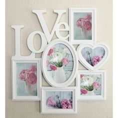 a white wall with pink flowers and pictures hanging on it's side, in the shape of a heart