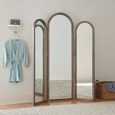 a room with three mirrors and a coat rack