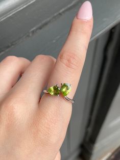 This ring is a brightly coloured, high clarity, natural stone Peridot ring. This ring consists of two small teardrop shaped stones that fit together, creating a unique, beautiful shape. The setting and band are sterling silver, with a white gold fill on top. Each stone dimensions are 8mm by 6mm at the widest points. The ring size is #7. Please let us know if you have any questions.  Stone hardness 6.5-7 / Source: Arizona, Egypt, China, Brazil, USA... Peridot is an olivine and silicate mineral, i Peridot Three Stone Ring, Green Three Stone Peridot Jewelry, Three Stone Peridot Ring, Green Peridot Three Stone Jewelry, Three Stone Peridot Ring Jewelry, Teardrop Green May Birthstone Ring, Green Teardrop Ring For May Birthstone, Green Teardrop May Birthstone Ring, Fine Jewelry Three Stone Teardrop