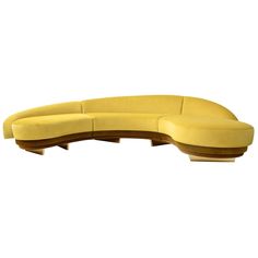 the curved couch is made from wood and has a yellow upholstered fabric on it