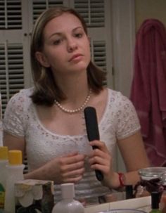 a woman holding a hairdryer in front of her face while sitting at a table