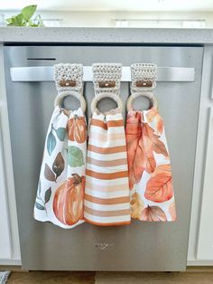 three kitchen towels hanging on the front of an appliance