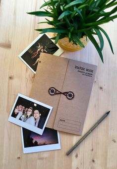 an open photo album sitting on top of a wooden table next to a potted plant