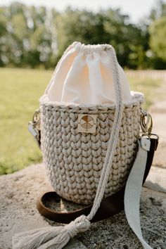 a crocheted bag sitting on top of a stone wall next to a grass field