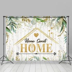 a white and gold backdrop with the words home sweet on it, surrounded by greenery