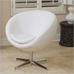 a white ball chair sitting on top of a wooden table next to a vase and lamp