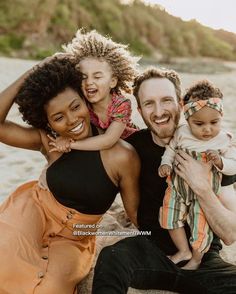 a man, woman and child are sitting on the beach with their arms around each other