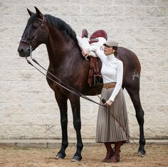 a woman standing next to a brown horse