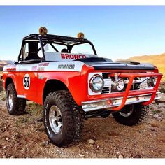 an old red truck parked on top of a dirt hill in the desert with mountains in the background