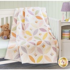 a baby crib with a teddy bear next to it and a blanket on the bed