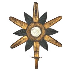 a gold and black metal clock with four leaves on it's face, in the shape of a star