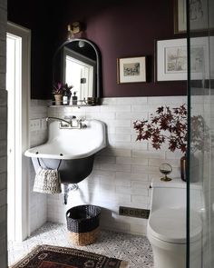 a white toilet sitting next to a sink in a bathroom under a mirror and a rug