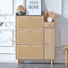 a wooden cabinet sitting next to a lamp on top of a hard wood floor covered in wicker