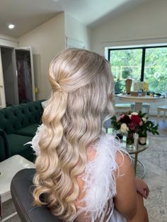 a woman sitting in a chair with long blonde hair and white feathers on her head