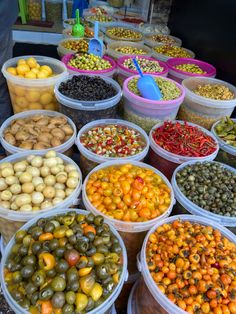 several buckets filled with different types of olives and other fruits on display at an outdoor market