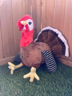 two stuffed turkeys sitting in the grass next to a fence