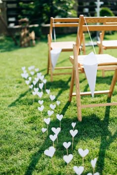 white paper hearts are placed on the grass next to wooden ladders and lawn chairs