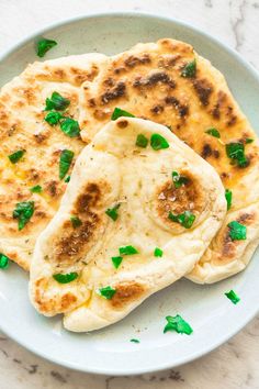 two flat breads on a plate with green herbs