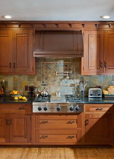 a kitchen with wooden cabinets and stainless steel appliances, including an electric range hood over the stove