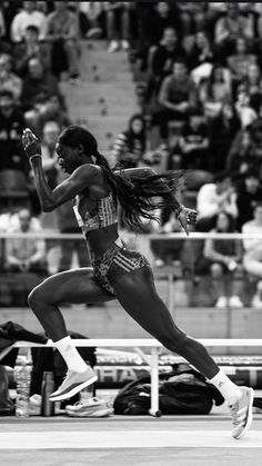 a woman running on a track in front of an audience