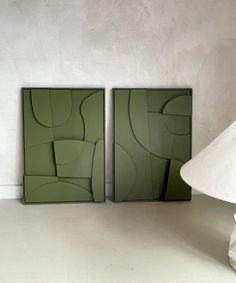 two green framed art pieces sitting on top of a white floor