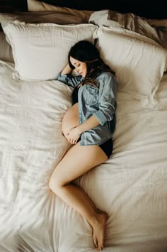 a pregnant woman laying on top of a bed