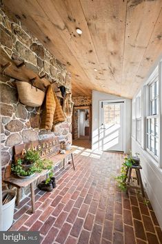 a brick walkway leads up to the front door of a home with potted plants and hanging baskets on the wall