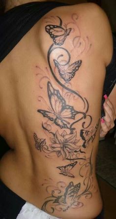 the back of a woman's body with butterflies and flowers tattooed on it,