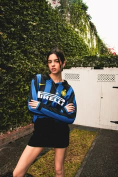 a woman standing in front of a fence wearing a blue and black shirt with the word freit on it