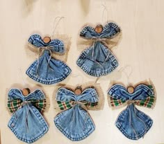 four pieces of blue jean fabric with bows and buttons hanging from strings on a wooden surface