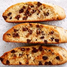 three pieces of bread with raisins and other toppings sitting on a napkin