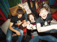 group of young men sitting on top of a couch with their hands in the air