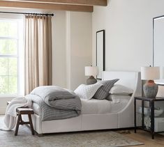 a white bed sitting in a bedroom next to a window