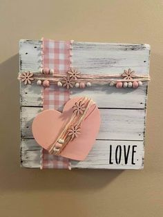 a wooden sign that says love with a pink heart and flower decoration on the front