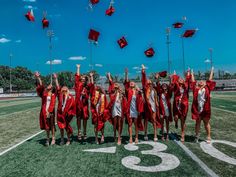 a group of graduates in red caps and gowns throwing their caps into the air