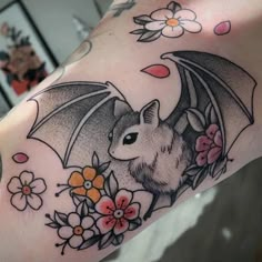 a bat tattoo on the arm with flowers