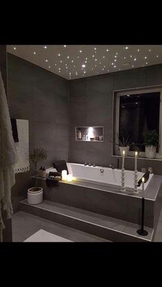 a bathroom with a large bathtub and lights on the ceiling, along with two candles