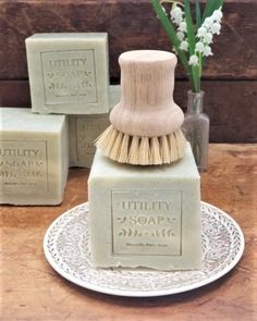 three soaps on a plate with some flowers in a vase next to one that says utility soap