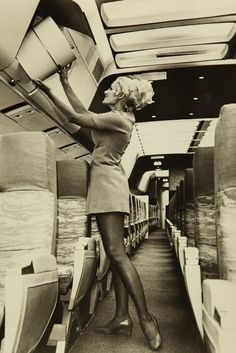 a woman standing in the aisle of an airplane with her legs hanging off the ceiling