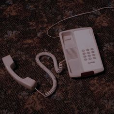 an old style telephone is laying on the floor next to it's corded phone