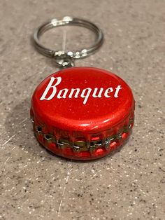 a red bottle cap keychain with the word banquet on it's side