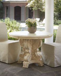 a white table and two chairs sitting on a patio with a house in the background