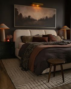 a large bed sitting in a bedroom next to two lamps and a painting on the wall