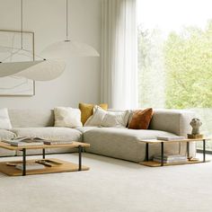 a living room filled with furniture and white carpeted flooring next to a large window