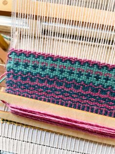 a weaving machine with several different colored yarns on it's warpning needles